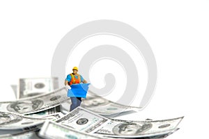 Miniature people toy figure photography. Project budget concept. A construction worker with blueprint building standing in the