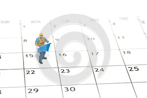 Miniature people toy figure photography. Project schedule time management concept. A construction worker holding blueprint