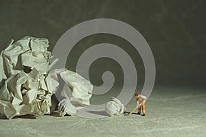 Miniature people toy figure photography. A sweeper cleaning office floor from rumple ball of paper