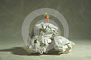 Miniature people toy figure photography. Tired sweeper standing above rumple ball of paper on the floor