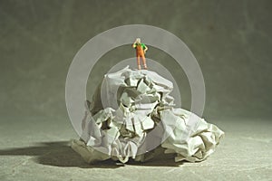 Miniature people toy figure photography. Tired sweeper standing above rumple ball of paper on the floor photo