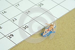 Miniature people toy figure photography. Travel plan schedule concept, men relaxing at beach chair with calendar