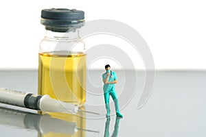 Miniature people toy figure photography. Urine test concept. A nurse standing in front of ampoule bottle and syringe