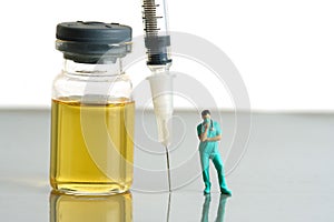 Miniature people toy figure photography. Urine test concept. A nurse standing in front of ampoule bottle and syringe