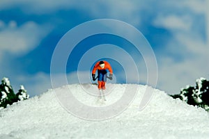 Miniature people toy figure photography. Winter sport. A male downhill ski racer slides down from the top of the hill
