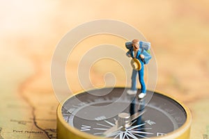 Miniature people: traveler stand on the compass to tell the direction of travel. Use as a business travel concept