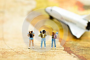 Miniature people: travelers with backpack standing on world map, travel by plane. Image use for travel business concept