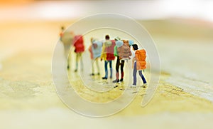 Miniature people, travelers with backpack standing on world map, walking to destination.