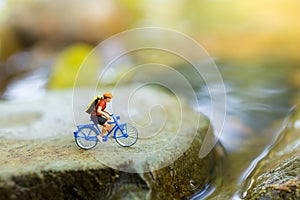 Miniature people : Travelers riding bicycle on the rugged road using as background traveling business concepts