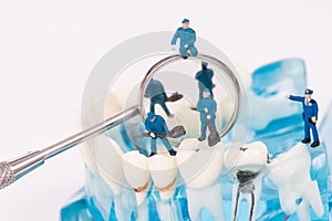 Miniature people use dental tool clean tooth or dental model