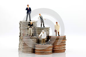 Miniature people with various occupations standing on coins money