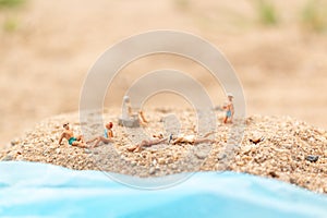 Miniature people wearing swimsuit relaxing on the beach