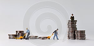 Miniature people at work site with stack coins. Concept of economic inequality.