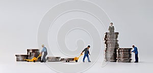 Miniature people at work site with stack coins. Concept of economic inequality.