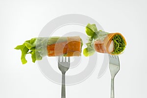 Miniature people worker digging into the salad of fresh vegetablSalad of fresh vegetables rolls on a fork isolated on white backgr