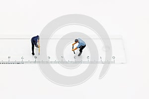 Miniature people: Worker digging white ruler. Service,  repair and  maintenance concept