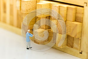 Miniature people : Worker push the wood log back into place. Image use for allocating space to stock, warehouse, business concept