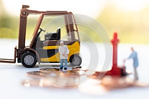 Miniature people: Worker use pallet truck with stack of coins. Image use for background business concept