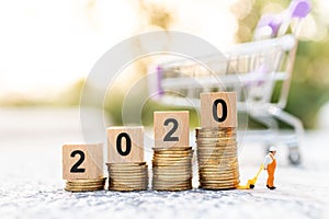 Miniature people: Worker use pallet truckwith stack of coins and wooden block  new year. Image use for logistic, retail business