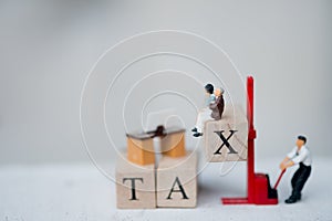 Miniature people worker wood word with TAX by forklift