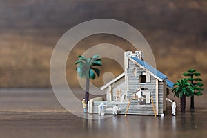 Miniature people: Workers team painting a new home