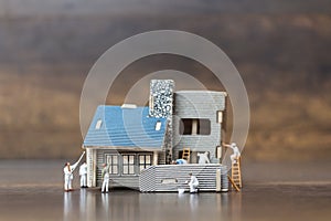 Miniature people: Workers team painting a new home