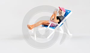 Miniature person relaxing on a deckchair