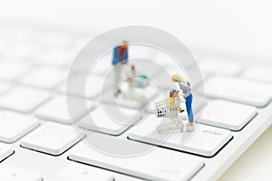 Miniature person: a shopper pushes a shopping cart on a shift button on white keyboard