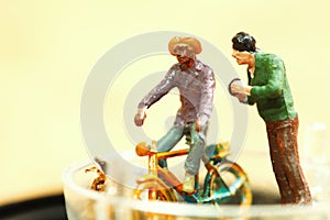 Miniature plastic figure model toy of man riding bicycle.