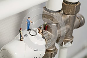 Miniature Plumbers Repairing A Thermostat