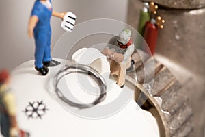 Miniature Plumbers Repairing A Thermostat