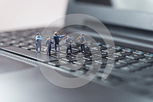 Miniature police squad protecting laptop computer. Technology concept