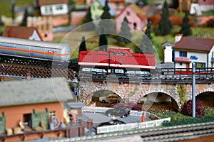 Miniature railway model with model freight train that passing on a viaduct on a mountains ambientation. Toy Train