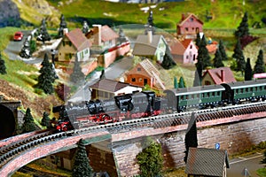 Miniature railway model with model steam locomotive train on a mountains ambientation. Toy Train
