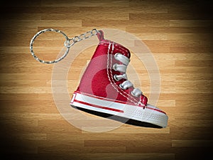 Miniature red baskeball shoe on wooden floor as background