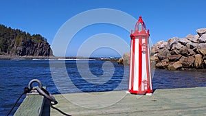 Miniature reproduction of white and red lighthouse on a pier at the St Lawrence river GaspÃ©sie QuÃ©bec Canada