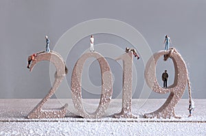 Miniature rock climbers scaling 2019 wooden blocks