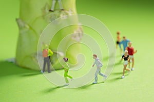 Miniature Runners jogging in a circle around a broccoli to train fitness and endurance