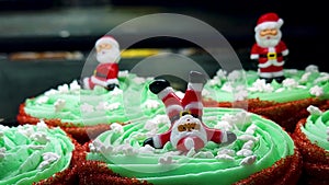 Miniature santa claus figurines were placed on top of green creamy icing for decorating christmas cookies