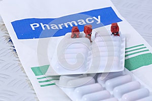 Miniature scale model chemical team with prescription antibiotics medicine in a blister pack on a Pharmacy paper bag.