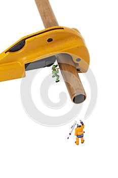 Miniature scale model construction workers with a copper pipe and a pipe cutter.  Plumbing industry concept