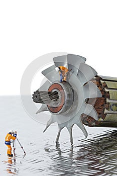 Miniature scale model construction workers with an industrial electric fan motor.