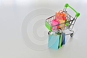 Miniature shopping cart with colorful shopping bags