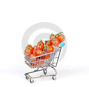 Miniature shopping cart filled with tiny cherry tomatoes isolated