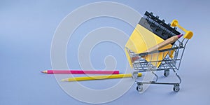 Miniature shopping cart with school supplies. Back to school concept.