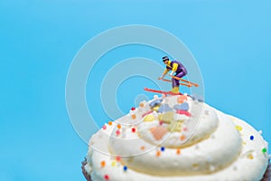 Miniature skier skiing down a cupcake