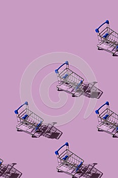Miniature supermarket trolley pattern on pink background. Place for text