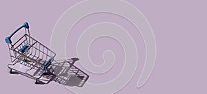 Miniature supermarket trolley on purple background. Place for text