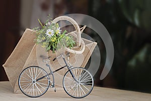 Miniature toy bike and flowers bouquet in canvas bag, concept of country summer and leisure