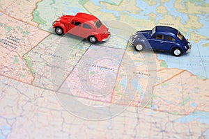 Miniature toy cars driving in tandem on a map of canada